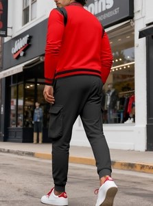 Tuta sportiva da uomo rossa con pantaloni cargo neri e sneakers bianche in stile street