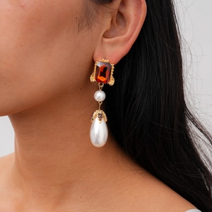 Close-up of vintage drop earrings with red rectangular gemstone and large teardrop pearl