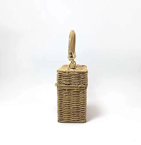 Detailed side view of the woven rectangular straw handbag with golden metal hardware