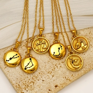 Double-sided 18K gold zodiac coin necklaces displayed on elegant textured stone