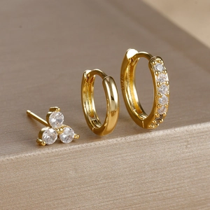 Macro shot of three-piece gold earring set featuring a clover stud and zircon hoops