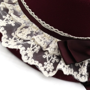 Close-up of wool felt bucket hat featuring elegant white lace trim and satin bow detail