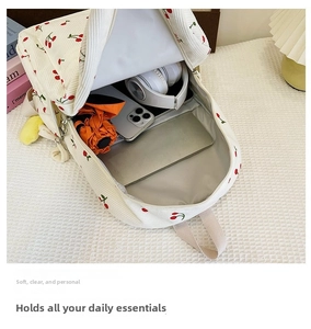 Interior view showing large capacity of white corduroy cherry print backpack with essentials