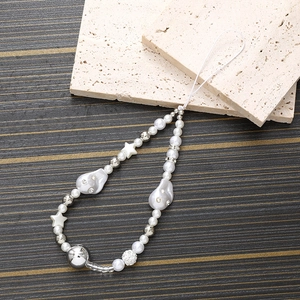 Irregular pearl phone strap with diamond skull and star charms on stone background