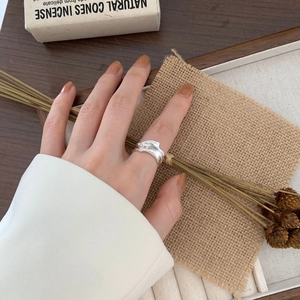 Close-up of textured irregular silver ring styled with natural wood and linen props