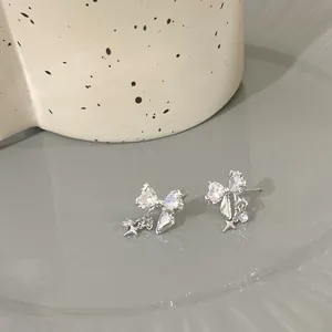 Détail de boucles d'oreilles nœud argentées avec zircons et pendentifs étoiles