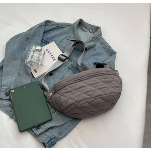Detail of grey quilted nylon crossbody bag with adjustable strap and black buckle