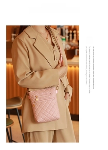 Pink quilted crossbody bag with golden zipper detail shown in a cozy indoor setting