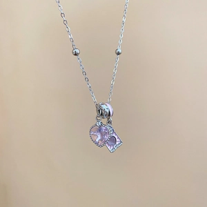 Macro detail of silver necklace with pink heart gemstone and enamel pendant