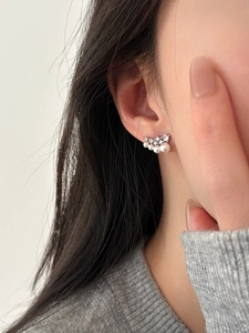 Detail of elegant silver needle earrings with gradient pearls and sparkling zircon accents