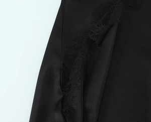 Close-up of exquisite black lace trim and satin fabric on an asymmetric dress