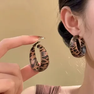 Close-up of retro leopard print resin oval hoop earrings worn by a model for a vintage look