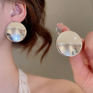 Détail de grandes boucles d'oreilles rondes en métal argenté au fini poli brillant