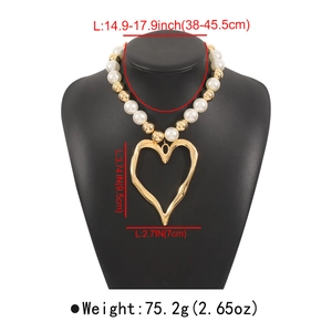 Detailed view of chunky necklace with large white pearls and oversized hollow heart pendant