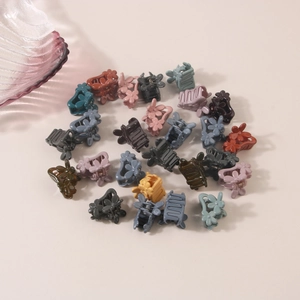 Flat lay of mini floral hair claws in various Morandi colors on a beige background