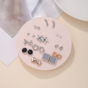 Flat lay detail of geometric star, butterfly and flower stud earrings with rhinestones