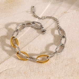Close-up of 18k gold and silver two-tone stainless steel beaded bracelet on stone