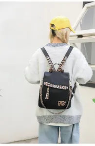 Close-up of a black nylon backpack with leopard print straps and gold hardware detail