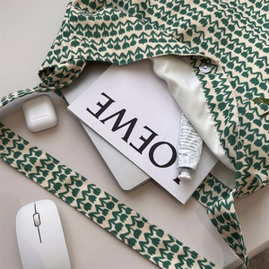Flat lay of floral cotton tote bag with green tulip print and tech accessories on desk