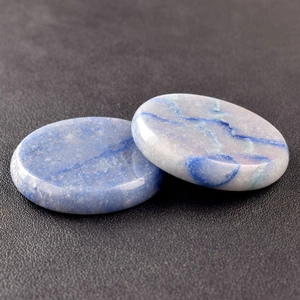 Close-up of natural blue and white flat round crystal energy stones on a black surface