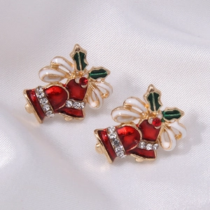Macro shot of festive Christmas bell stud earrings with enamel holly leaves and red rhinestones