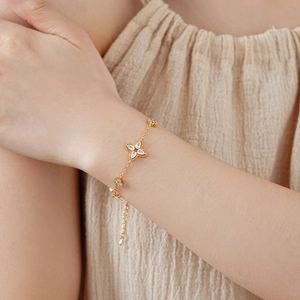 Detail of a gold clover bracelet with marquise-cut zircons worn on a female wrist