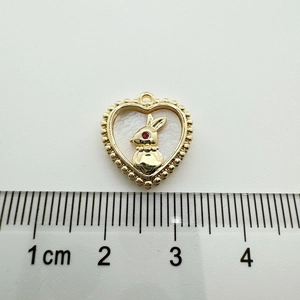 Close-up of 18K gold-plated rabbit heart pendant with white inlay and scale measurement