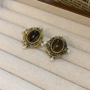 Détail macro de boucles d'oreilles vintage dorées avec pierre œil de tigre et perles