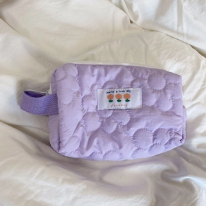Dettaglio di un astuccio trapuntato viola con cuciture floreali e toppa decorativa