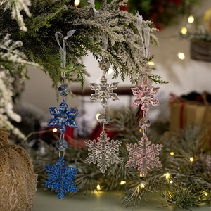 Three acrylic hexagon snowflake ornaments in blue, clear, and pink on a Christmas tree