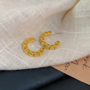 Chic geometric gold C-shaped earrings with textured square pattern on neutral background