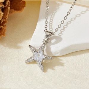 Macro shot of a silver starfish pendant with sparkling cubic zirconia on white stone