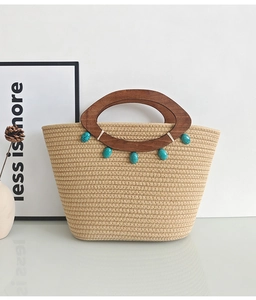 Detail of woven beige tote bag featuring round wooden handles and turquoise bead accents