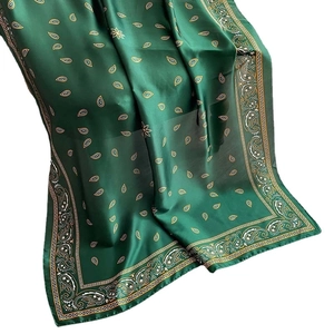 Elegante sciarpa di seta verde con motivi paisley dorati drappeggiata su sfondo bianco