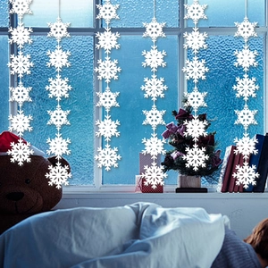 White snowflake garland hanging in a cozy Christmas bedroom setting with warm decorations