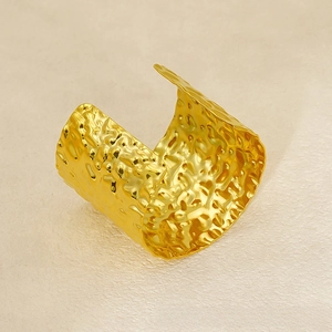 Macro detail of wide 18K gold plated stainless steel cuff with hammered texture finish