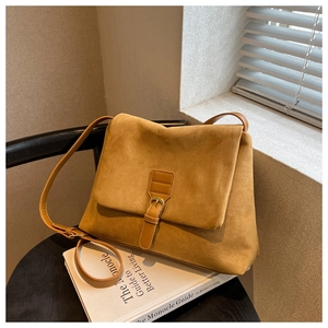 Dettaglio di una borsa a tracolla in pelle scamosciata color cammello con fibbia decorativa