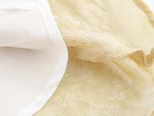 Détail du tissu en dentelle jacquard et des coutures de la robe beige à col en V