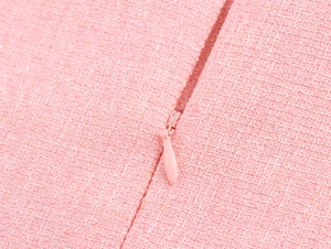 Detail shot of a pink tweed dress showing the high-quality invisible zipper and woven fabric