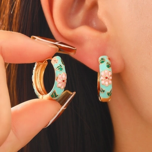 Detail of vintage floral enamel earrings with pink flowers and gold trim on model