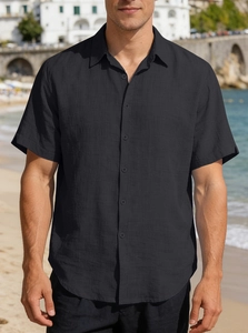 Close-up of black short-sleeved button-down shirt collar against a beach background
