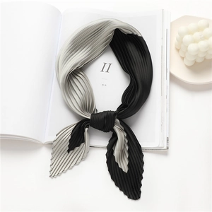 Detail of pleated silk scarf with black and grey color block design on a magazine