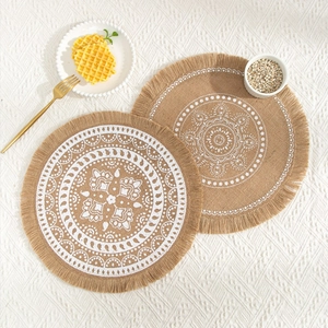 Detail of round jute placemats with white mandala patterns and decorative fringe edges