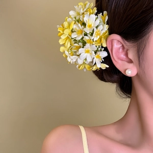 Detail view of yellow and white floral hair clip worn on a side bun vacation hairstyle