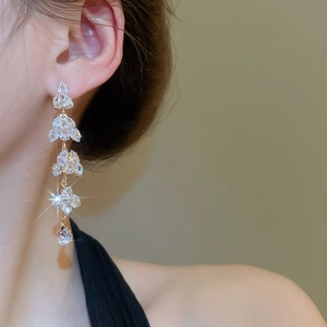 Detailed view of long gold tassel earrings with layered pear-cut clear sparkling zircons