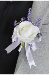 Detailed view of handmade white rose corsage with lavender accents on a suit lapel