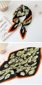 Detail of pleated silk scarf featuring floral prints and orange serrated edge