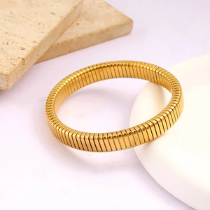 Close-up of golden tubogas style elastic bracelet with textured stainless steel surface