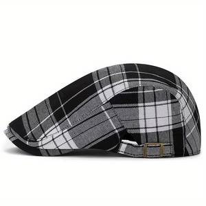 Plaid newsboy cap in black and white with adjustable bronze buckle on plain white background