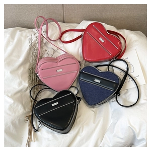 Detailed flat lay of heart-shaped crossbody bags in pink, red, black, and denim finishes
